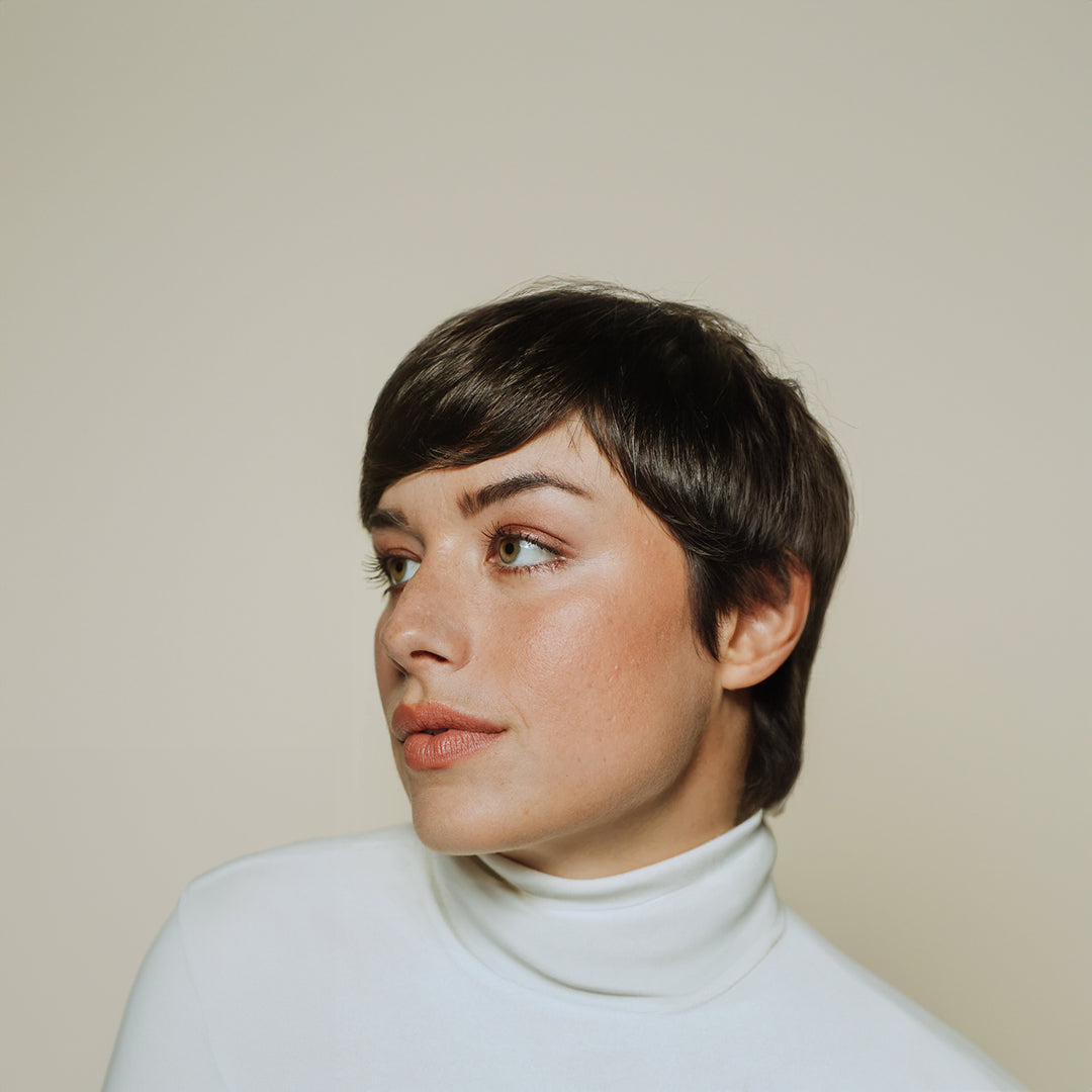 woman with short hair looking to her right on a beige background