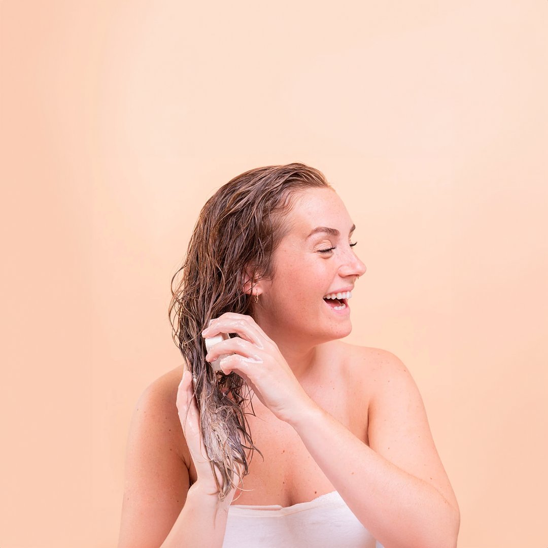 lady washing her hair against a peach background