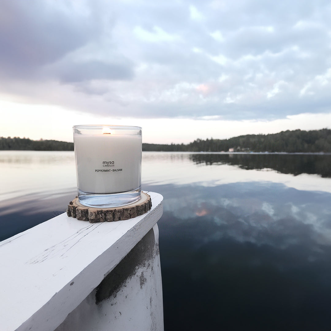 candle in a whiskey glass at the lake on wood painted in white