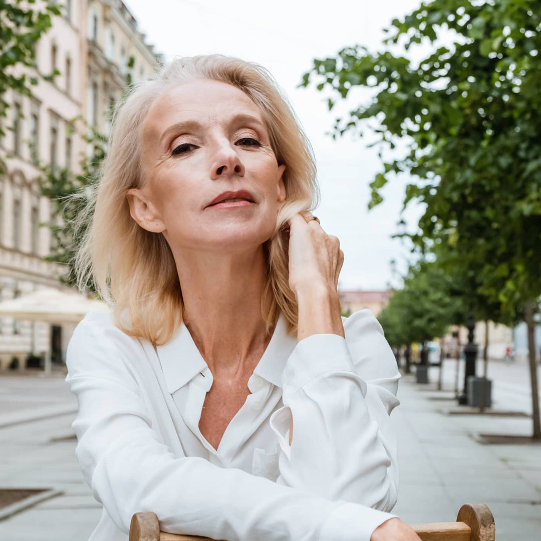 woman seated outside looking confident with great skin at a mature age