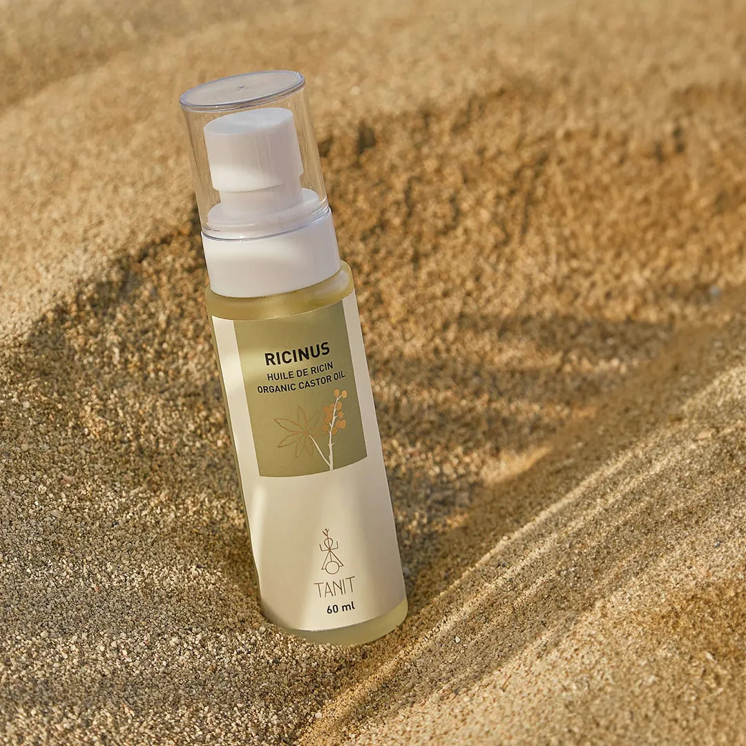 tanit castor oil lifestyle bottle in beach sand