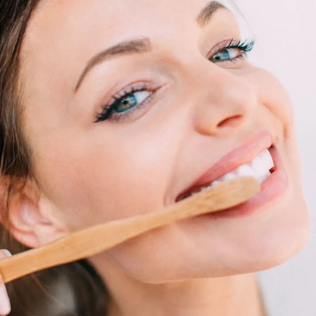 a woman brushing her teeth with a tanit's bamboo toothbrush